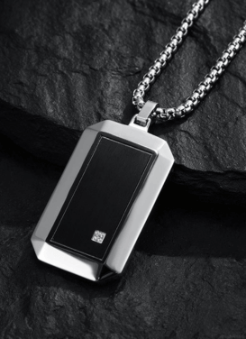 Elegant men’s necklace with a sleek black pendant on a rugged stone background, perfect for stylish accessorizing.